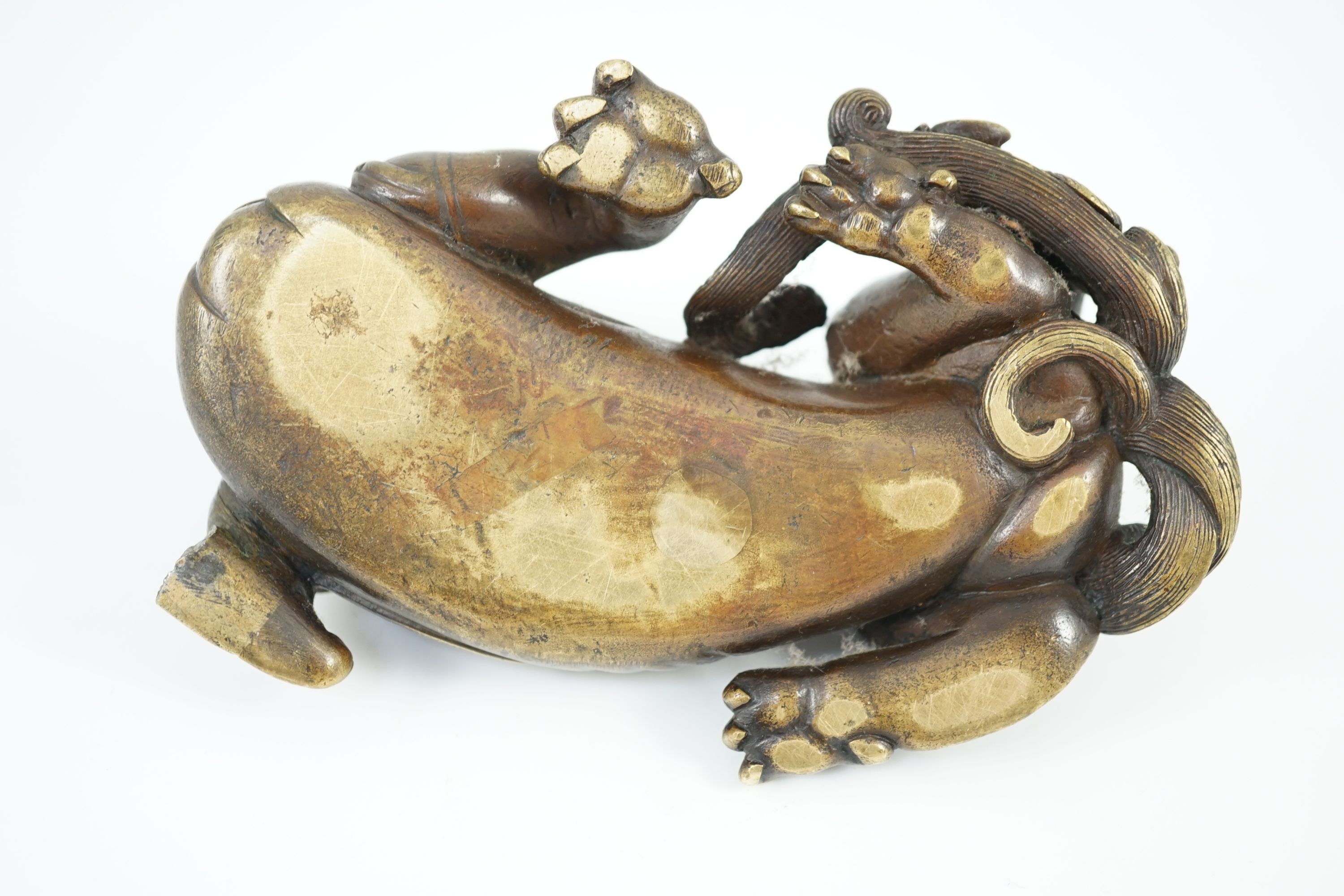 A finely cast Chinese bronze lion-dog and cub scroll weight, 17th/18th century, 14cm long, one foot and a cub lacking